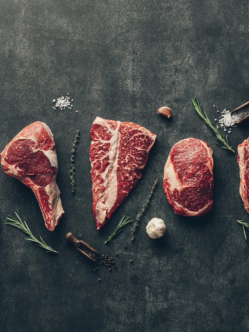 Raw beef cuts laid out on slate